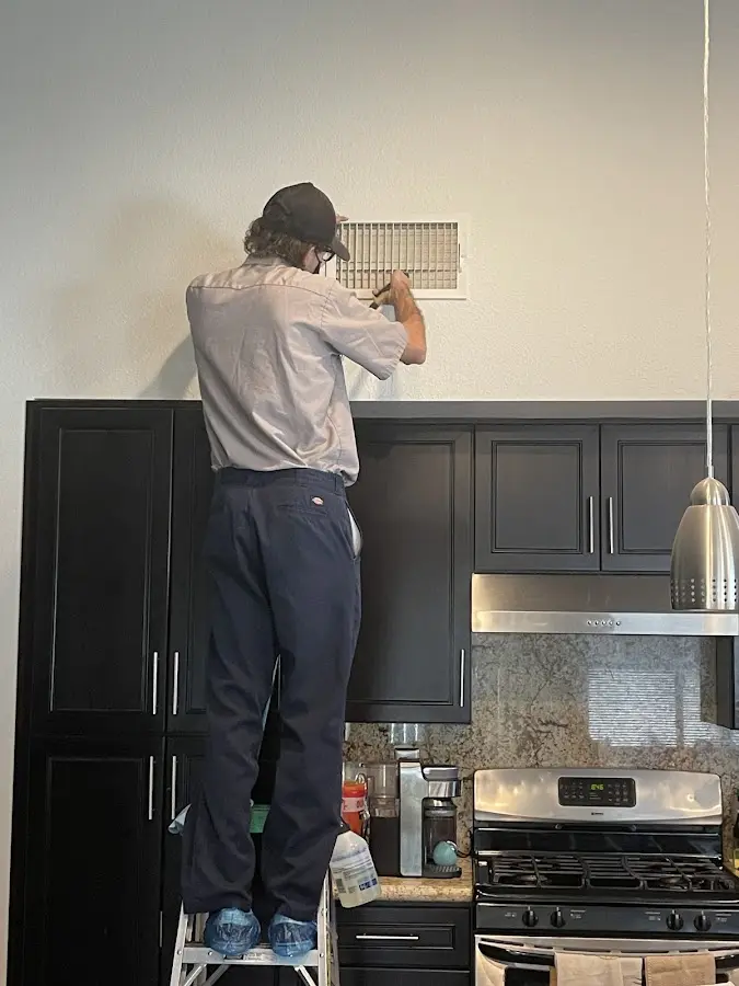 Technician inspecting an air vent during HVAC service in Windsor